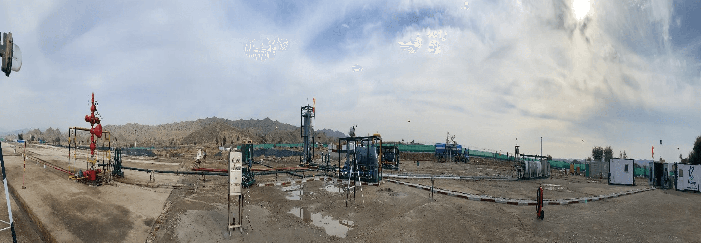 Panoramic view of desert wellsite with wellhead, separator package, and flowlines